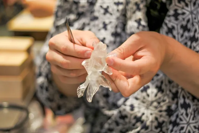 Hands shaping a clear candy fish with a small tool