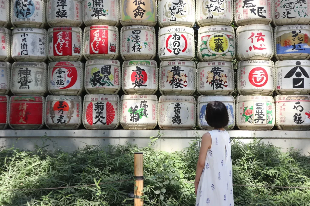 Decorative sake barrels displayed along a wall with a visitor standing nearby