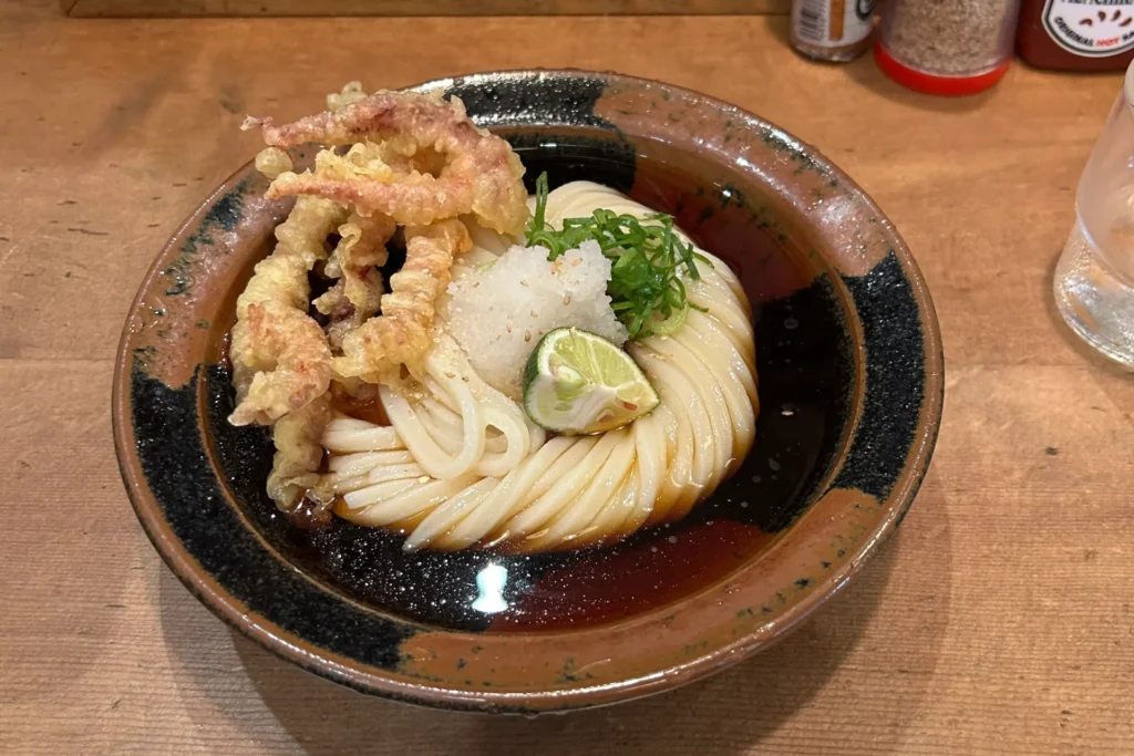 Cold bukkake udon topped with squid tentacle tempura, grated daikon, and green onions at Mensho