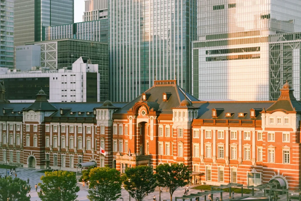Tokyo Station Marunouchi building in warm light with modern office towers behind it