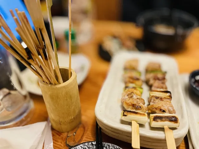 Grilled yakitori skewers served on a plate with extra skewers in a holder