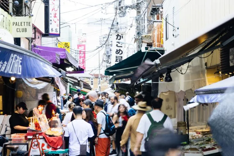 A crowded market street lined with small shops and food stalls