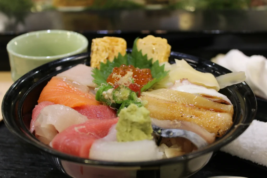 A bowl topped with assorted sliced seafood, tamagoyaki, salmon roe, and wasabi